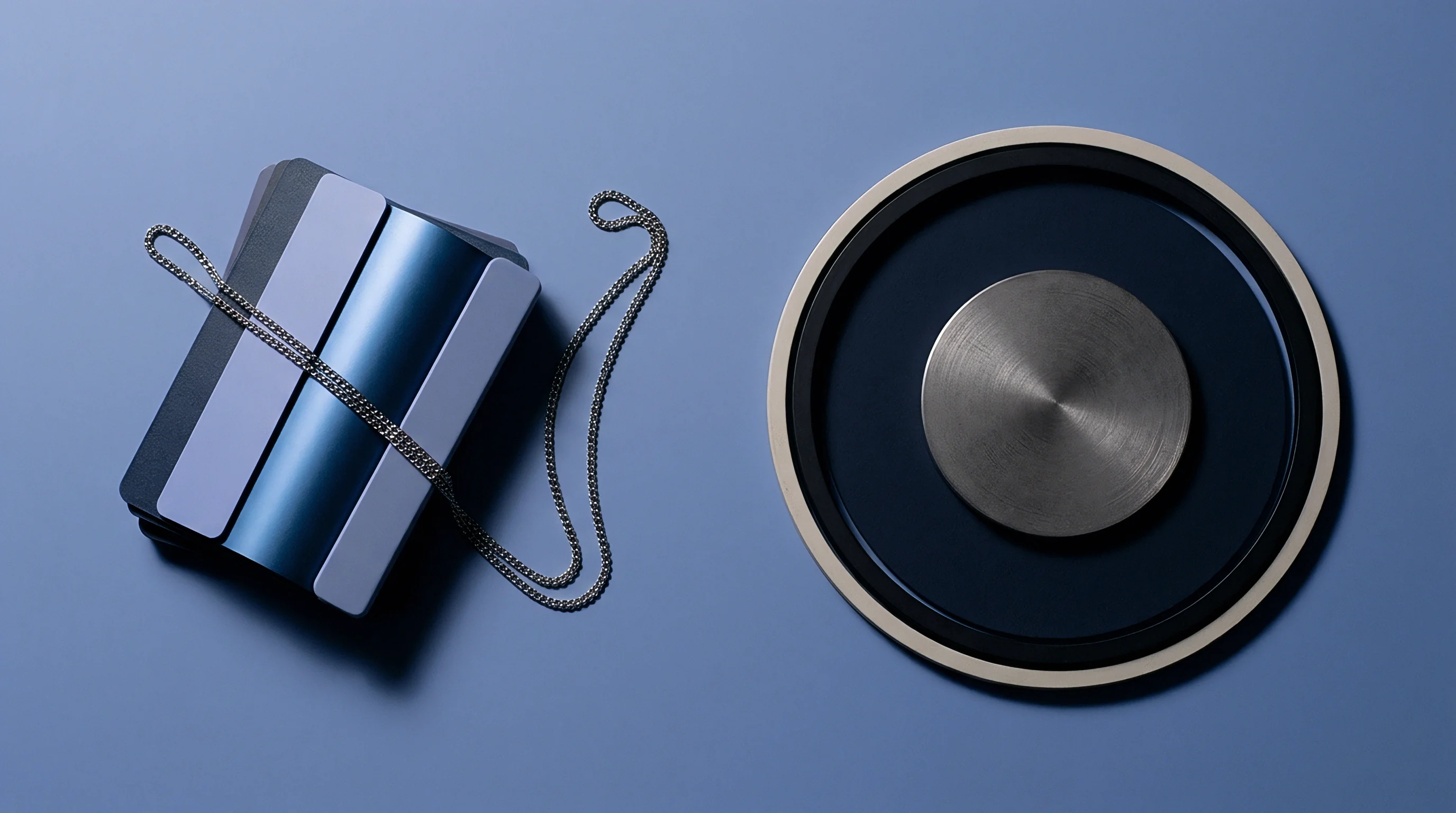 Molded polymer material swatches accompanied by a metallic chain and concentric circular components lie arranged on a matte blue production surface.